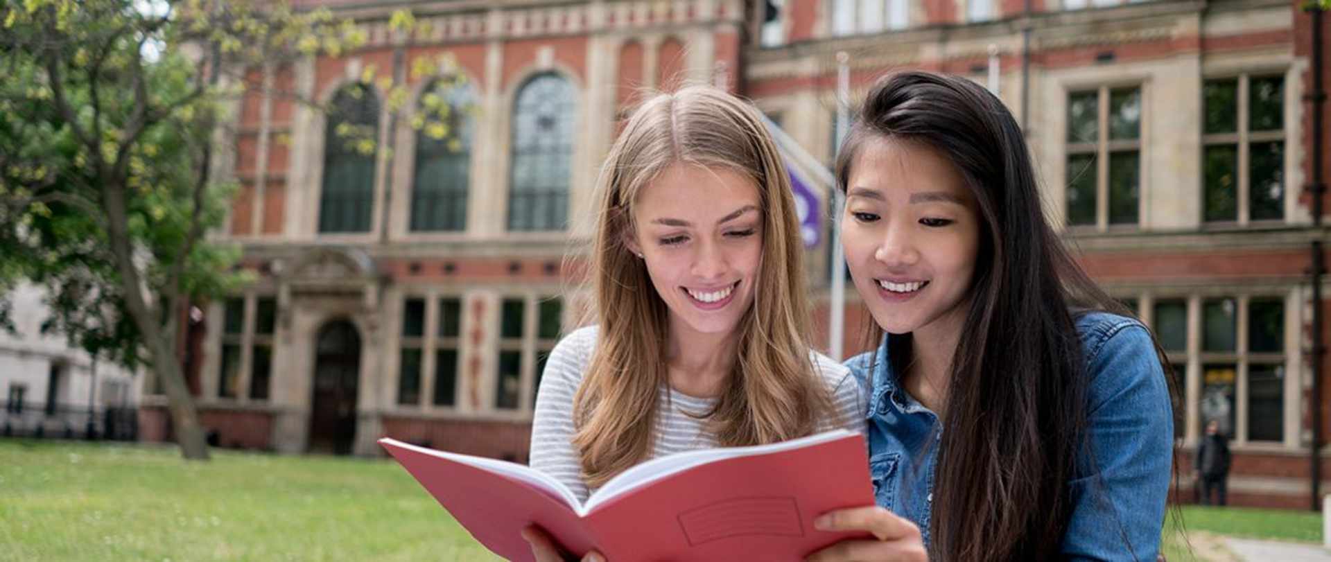 Two girls looking at a school workbook.