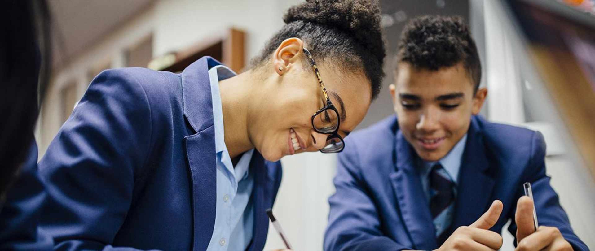 Two secondary school children writing notes.