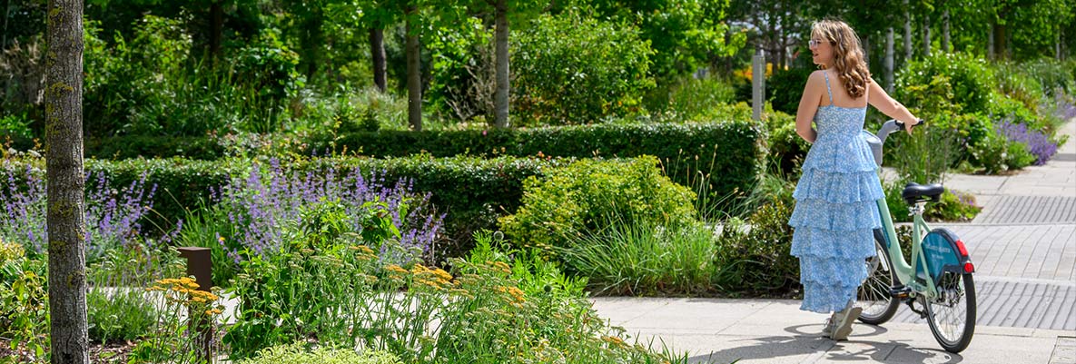 An image of a woman walking around The Green Quarter with her Bike
