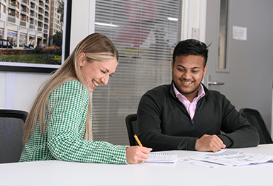 An image of people working on some paper work together