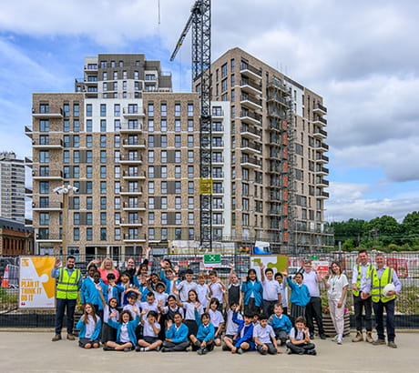An exterior image of a development under construction and children sat infront of it