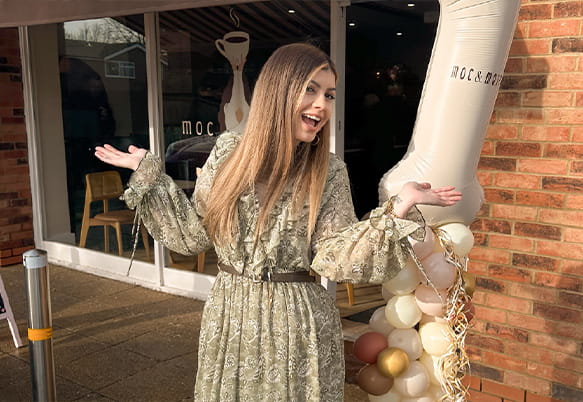 An image of a woman posing for a photo outside her cafe business