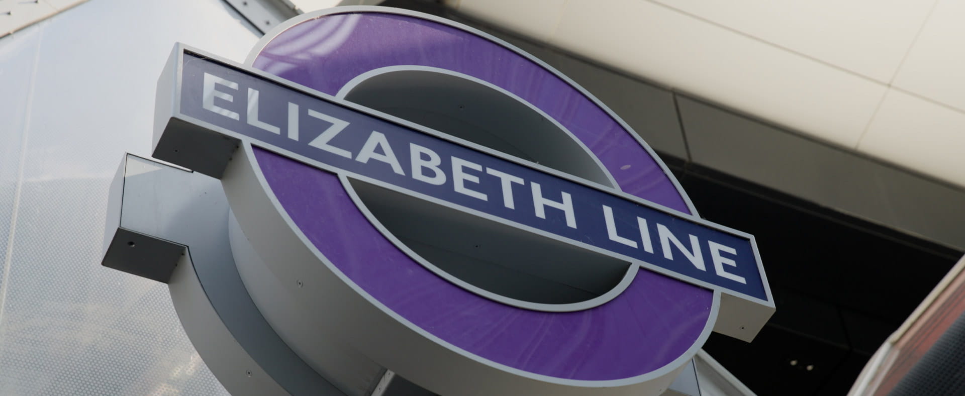 A sign for the Elizabeth Line outside a station, featuring a purple rim and blue strip with ‘ELIZABETH LINE’ text inside.