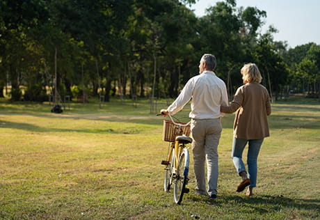  A couple walk through a park with a bicycle