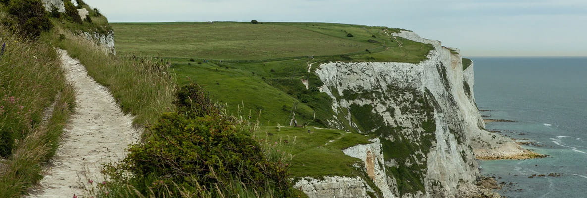 A scenic view of The White Cliffs of Dover, featuring a dramatic cliff face that meets the sea. 