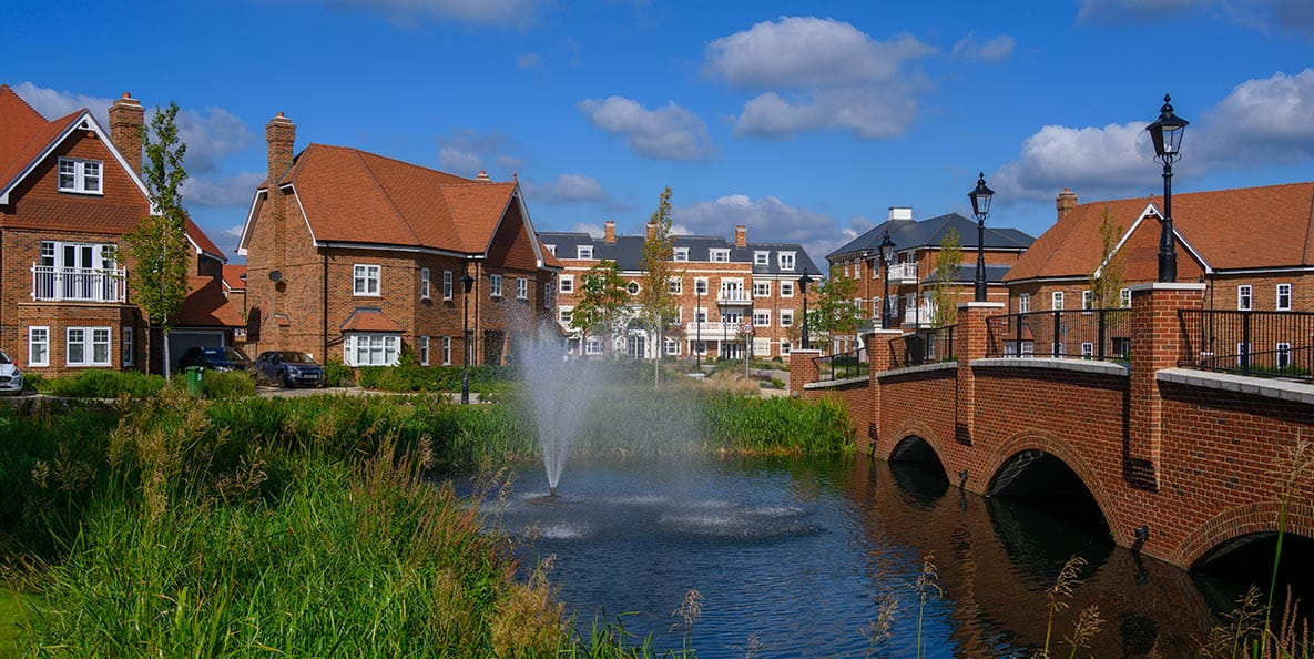 Homes overlooking a lake with a water feature at Hartland Village, Hampshire.