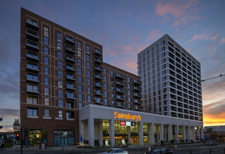 A development block of new build flats with a Sainsbury's convenience store in front.