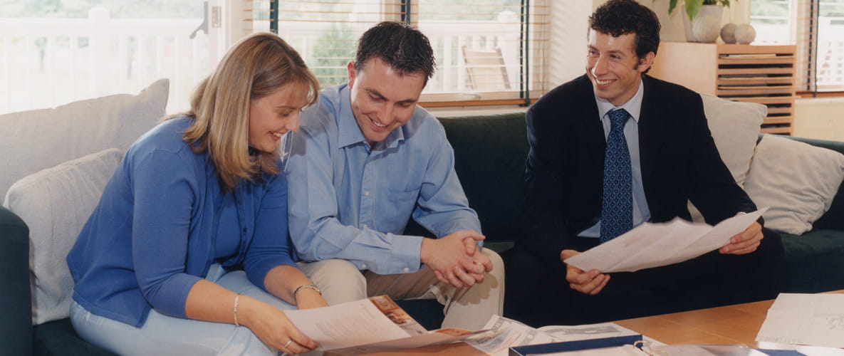 Couple looking through paperwork with sales consultant for buying a house