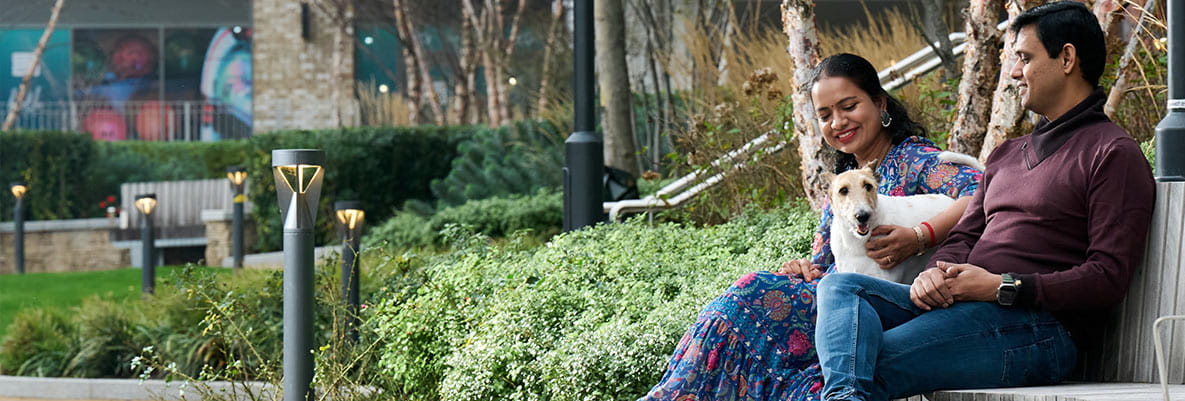An image of the couple sat outside on a bench with their dog