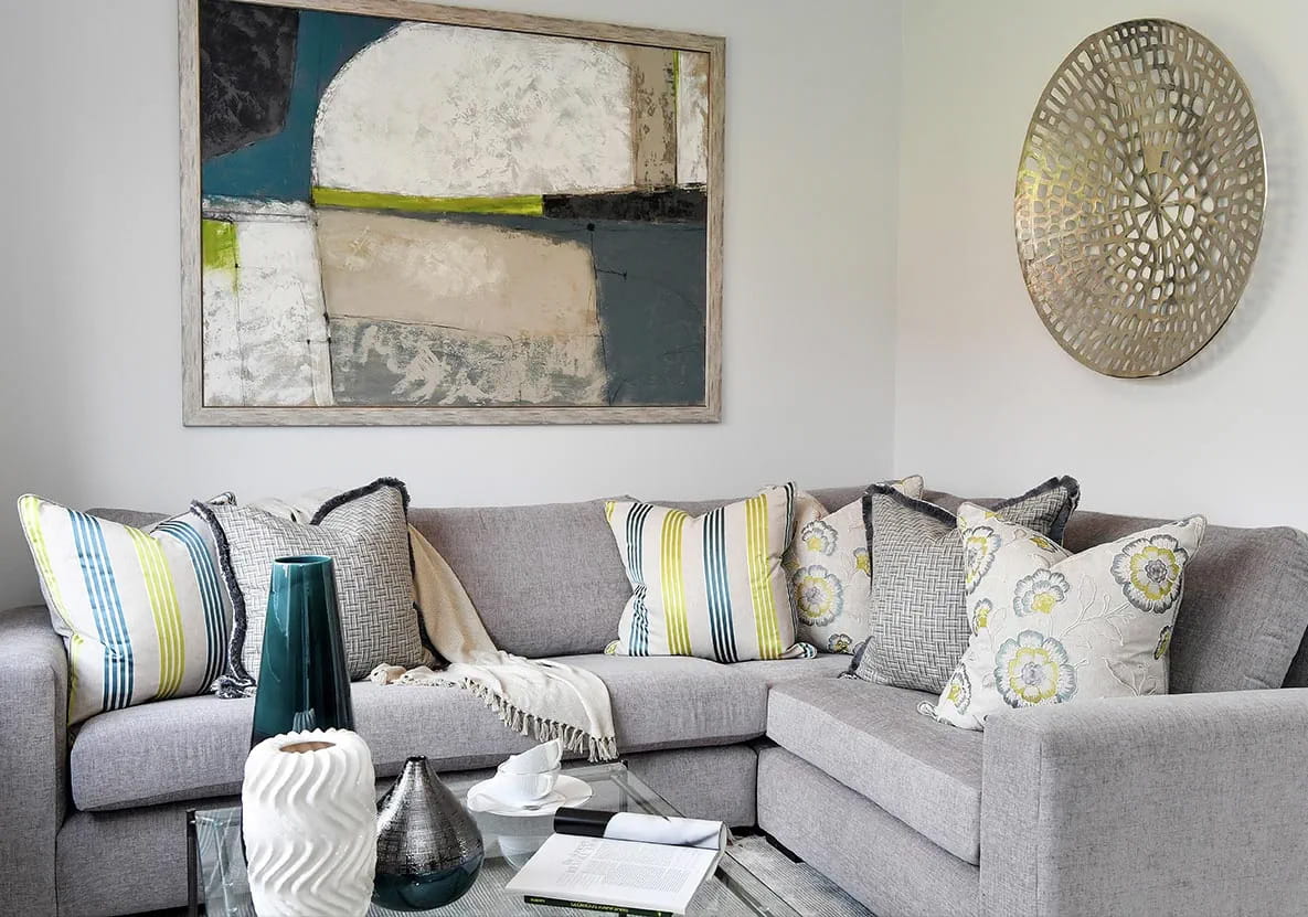 A large grey corner sofa decorated with cushions and a blanket.