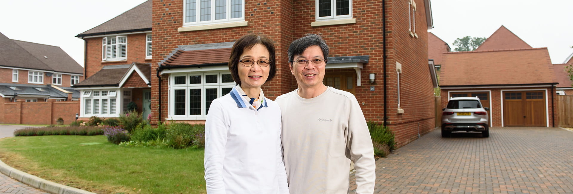 Dr Lena Chan and her husband, Wayne Lo, standing in front of their new home at Leighwood Fields development in Cranleigh, Surrey.