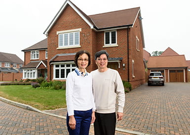 Dr Lena Chan and her husband, Wayne Lo, standing in front of their new home at Leighwood Fields development in Cranleigh, Surrey.