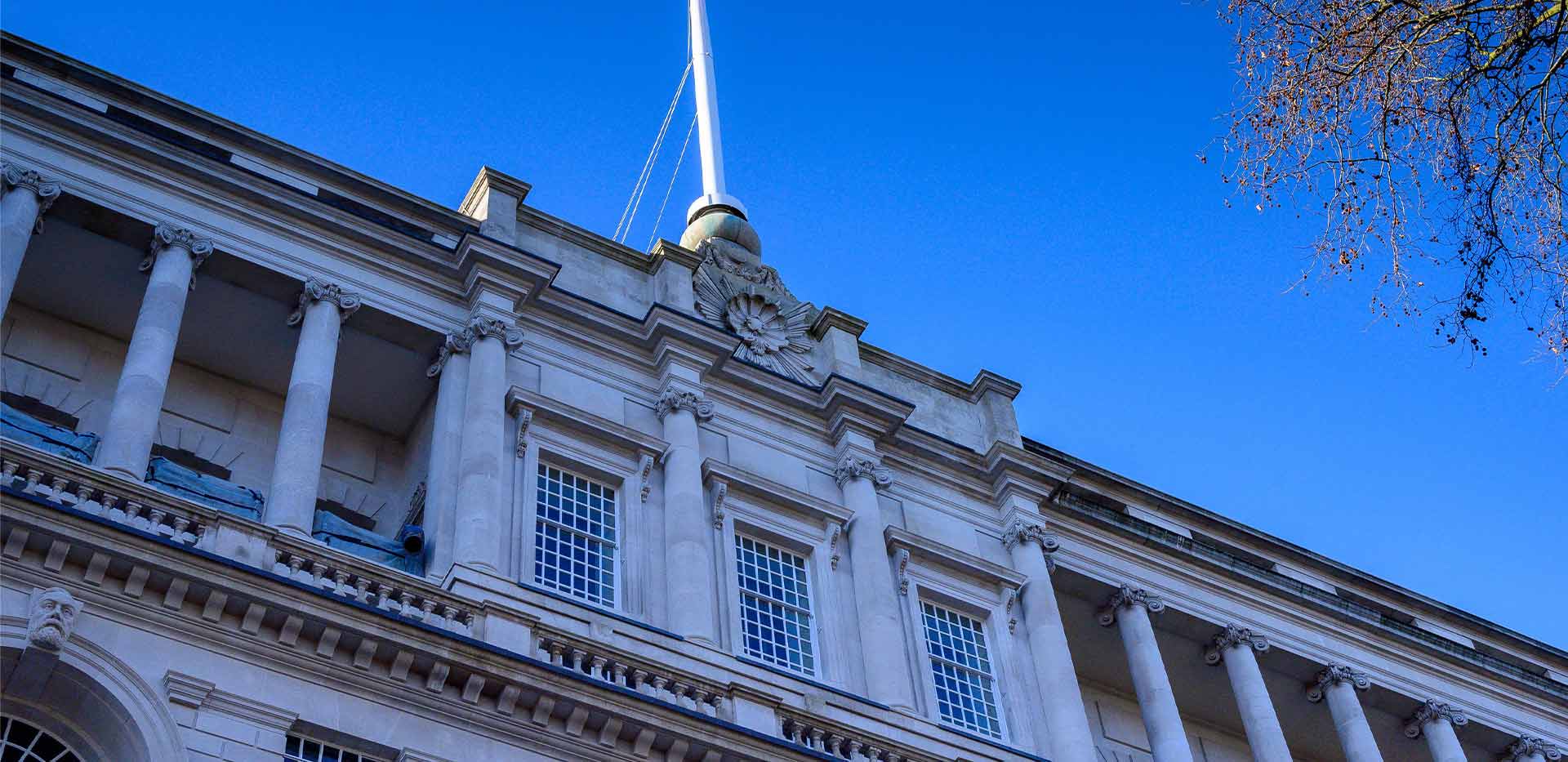 The exterior of the building at 9 Millbank. Large pillars and a granite-and-stone façade are a reminder of its 1930s roots.