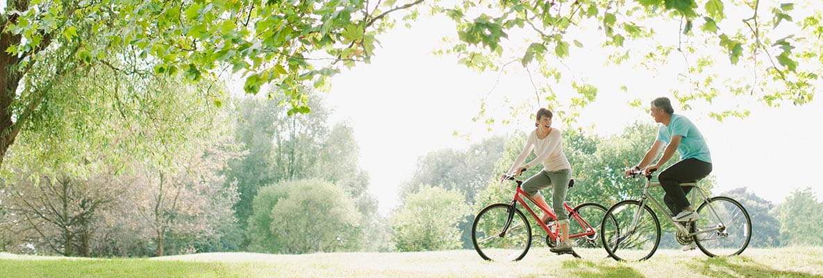 An image of a couple riding bikes in a park together