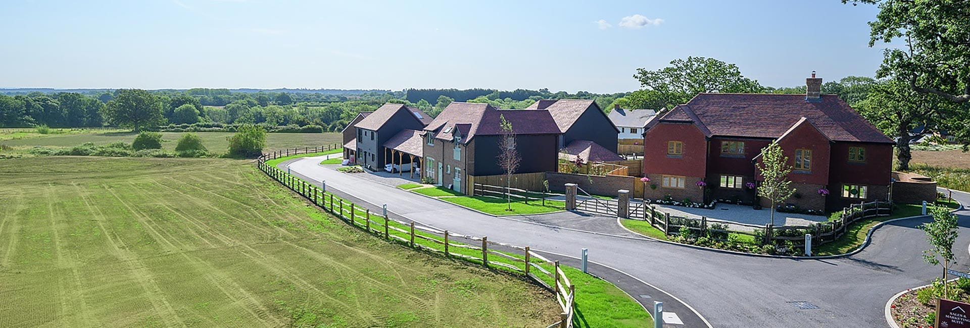 An aerial view of a residential development surrounded by green fields and trees