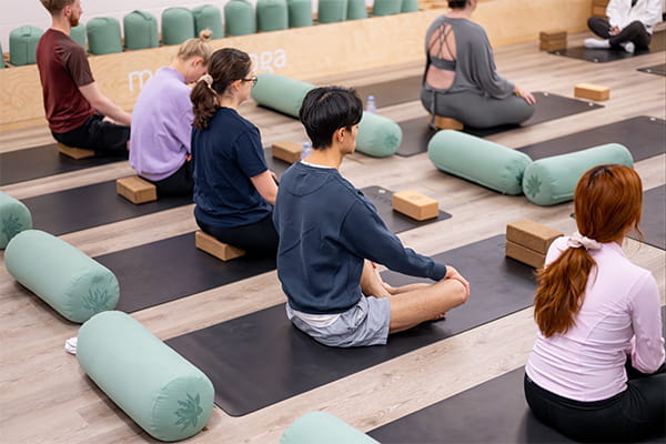 a pilates class in progress, attendees sitting cross-legged on mats.