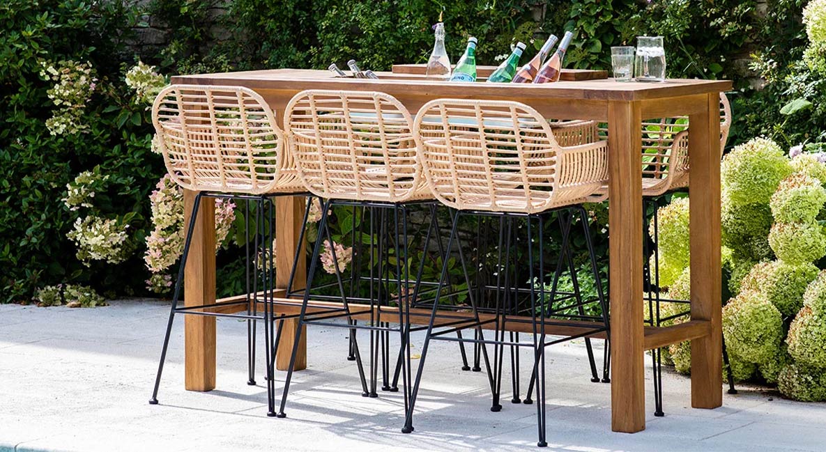 An outdoor bar table with woven rattan bar stools.