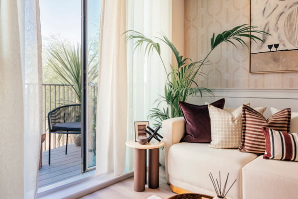 Closeup of sofa, end table, plants for decoration, adjacent to balcony.