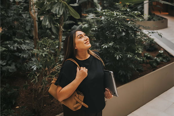 Faiza posing in communal area with lush green plant beds.