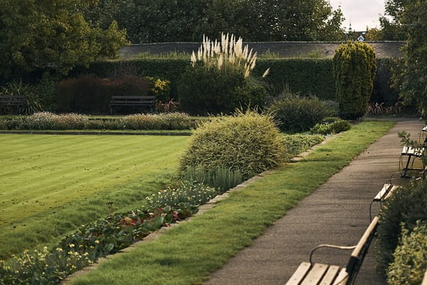 Tranquil park with manicured lawn, flowerbeds and wooden benches.