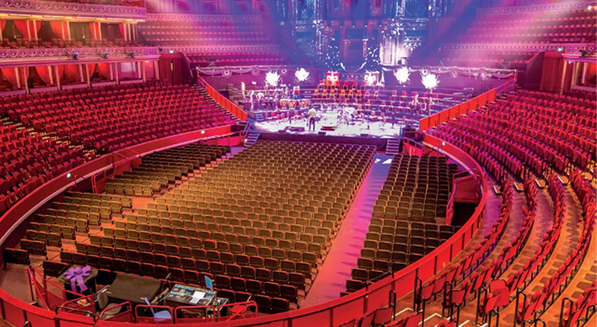 The distinctive interior of the Royal Albert Hall with circular seating arranged in multiple tiers, including stalls, boxes and a large balcony.