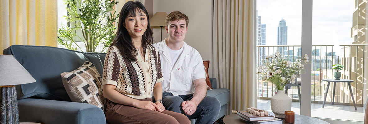 A photograph of Summer and Jonathan sat on the sofa in their new home at Oval Village
