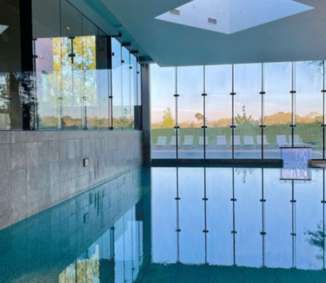 The modern interior of Ockenden Manor, featuring an indoor swimming pool that overlooks the hotel’s scenic grounds.