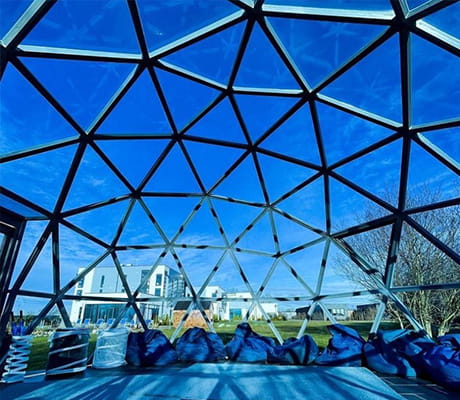 The signature glass dome construction of the Glass House Retreat in Essex, complemented by blue skies in the background. 