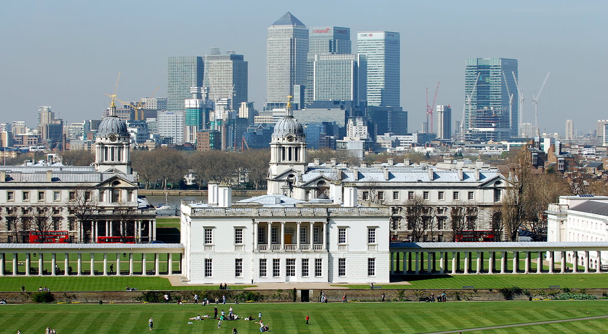 A high-up perspective of Greenwich Park with skyscrapers in the background.