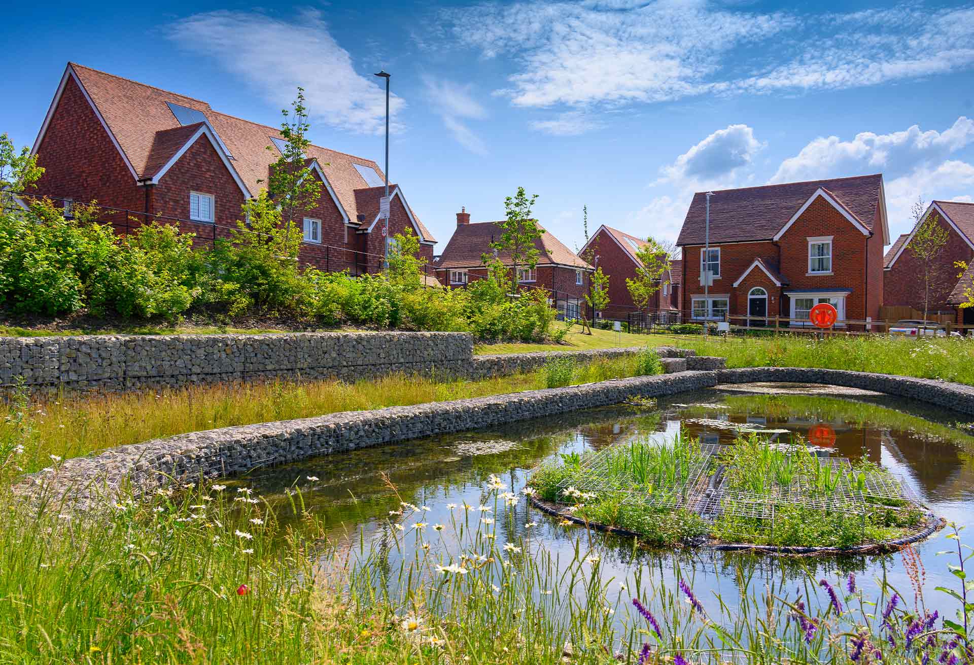 A group of redbrick houses surrounded by greenery and a pond