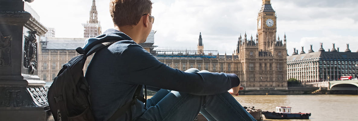 An image of a man sat on a wall looking over the Thames