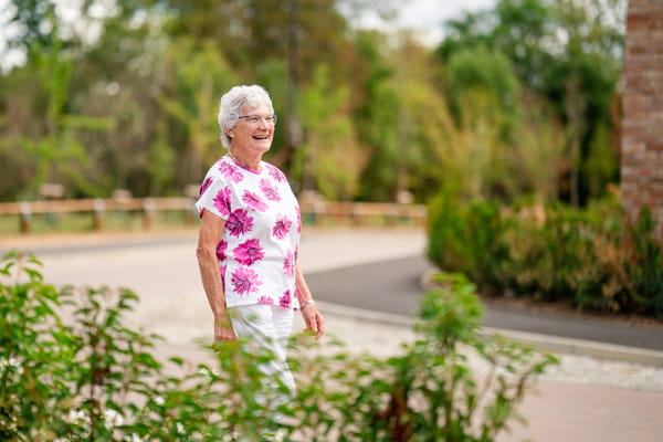 Elizabeth walking along road with newly planted landscaping adjacent.