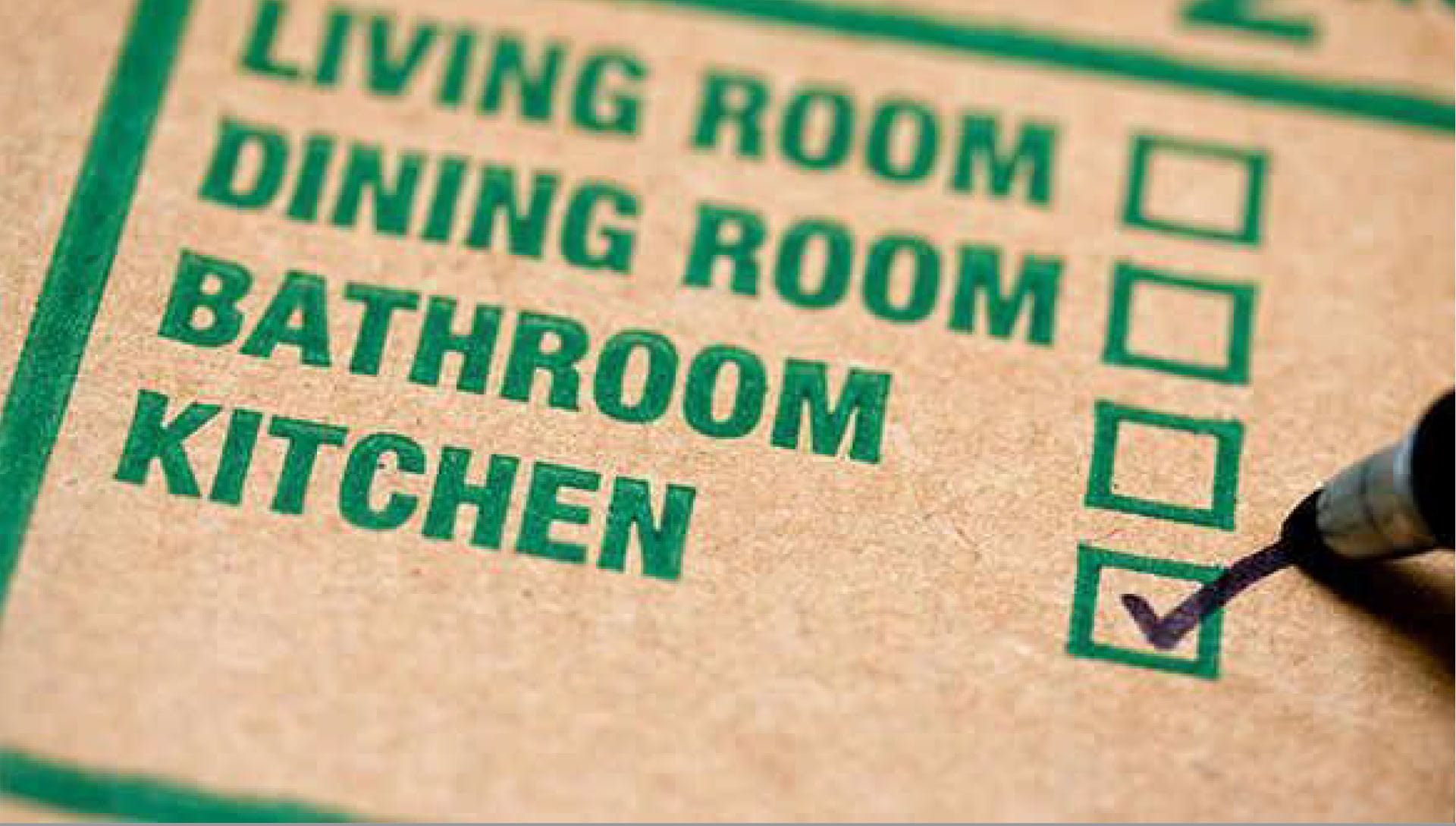 A cardboard box labelled, featuring a ‘Kitchen’ checkbox ticked with a marker.