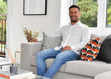 An image of a person sat on the Sofa of his new home