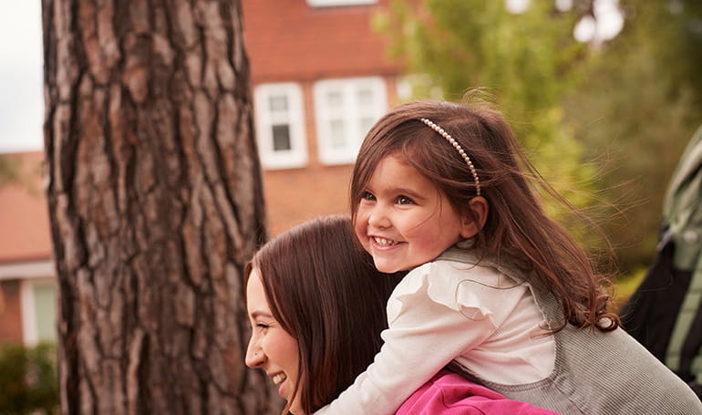 A mother carrying her child on her back outside their new home