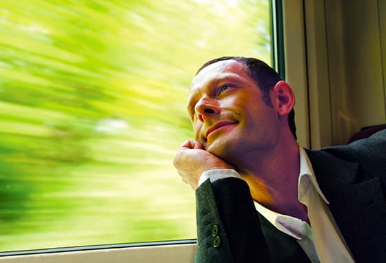 A man commuting from Hampshire to London. He is leaning on his chin looking out a window