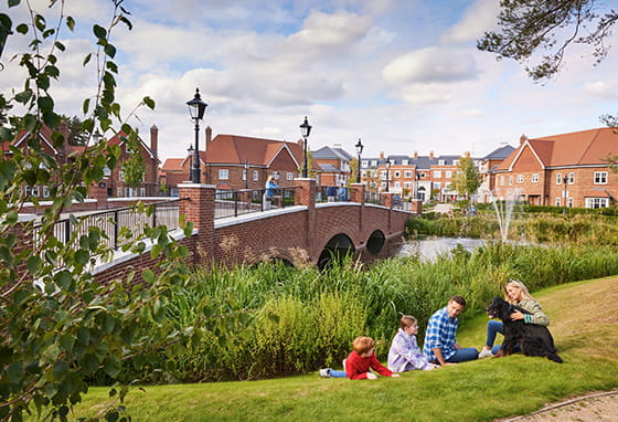 A group of people sitting on grass with a dog at Hartland Village, Hampshire