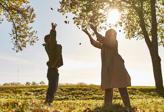 A woman and a boy throwing leaves in the air at Winterbrook Meadows, Oxford