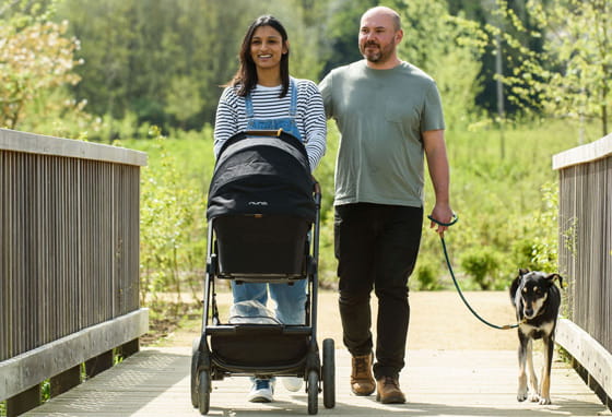A young couple with a baby, walking in Knowle Park near their new home at Leighwood Fields, Cranleigh