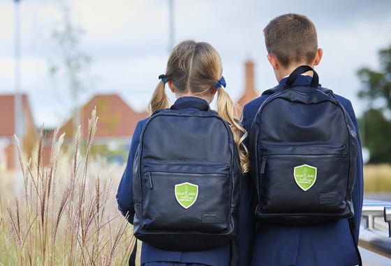 School children outdoors in a rural village setting surrounded by tall grasses