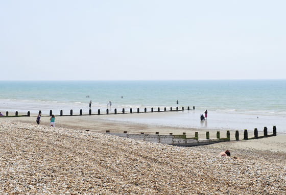 Pebble beach on the West Sussex coast with wooden groynes and calm sea
