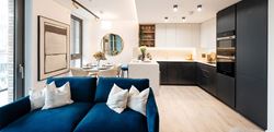 Living and kitchen area with a neutral design and a blue, central sofa