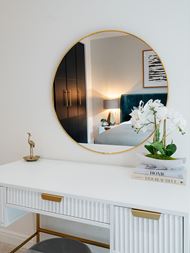 White dresser with a round mirror above
