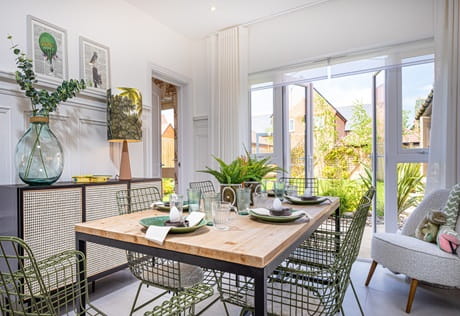Dining room with wooden table and chairs, chest of drawers, patio doors leading to garden