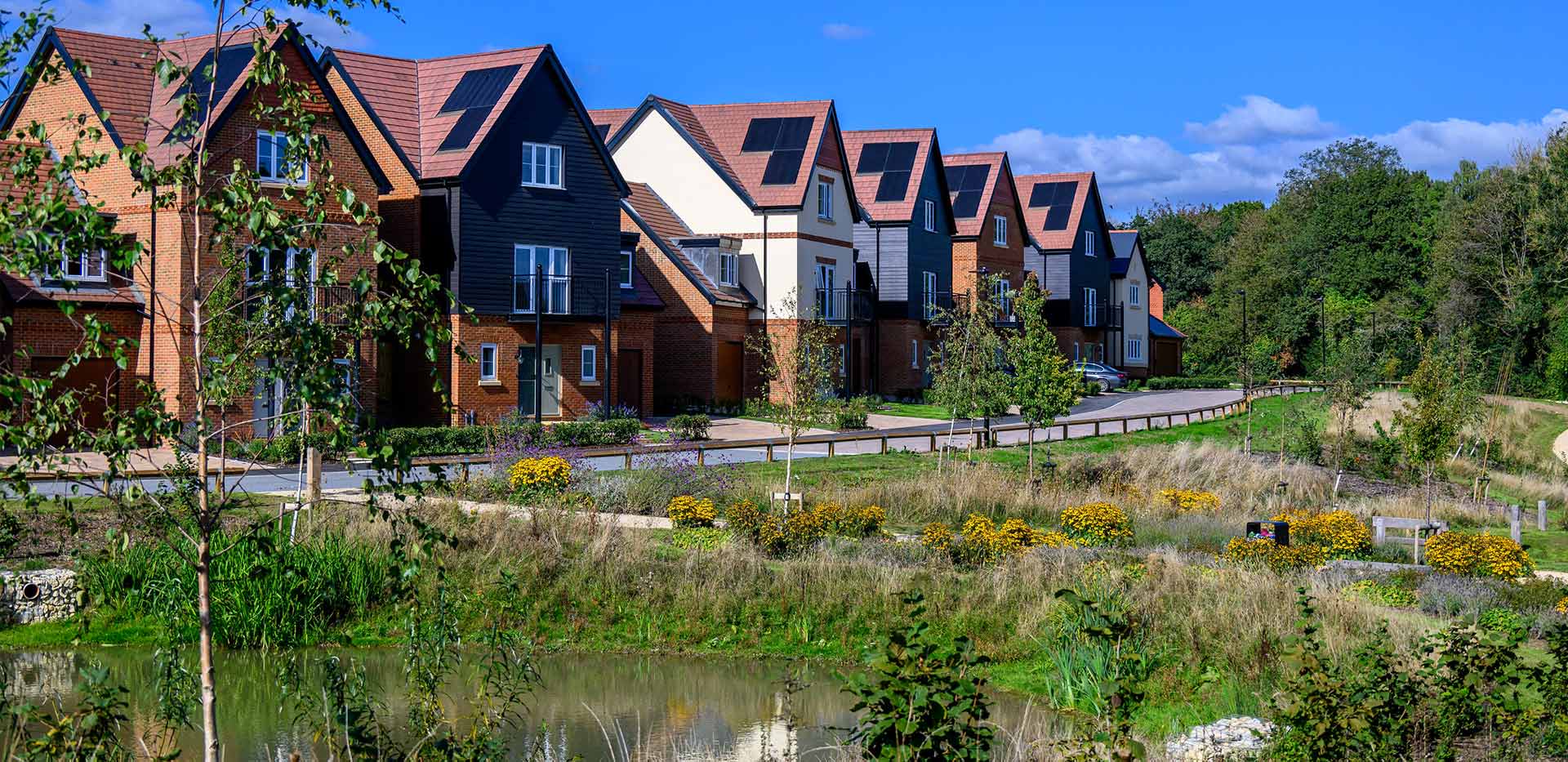 A row of houses at Abbey Barn Park with a pond and green space in the foreground