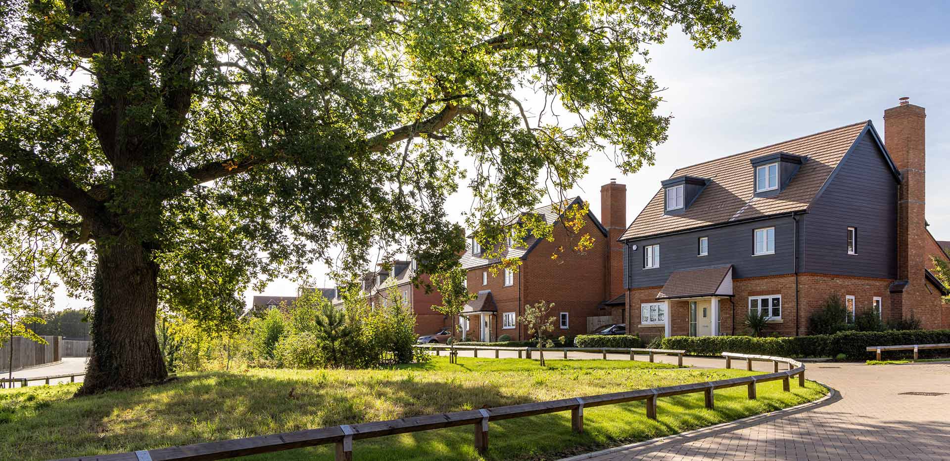 An image of a tree in front of a row of houses at Abbey Barn Park