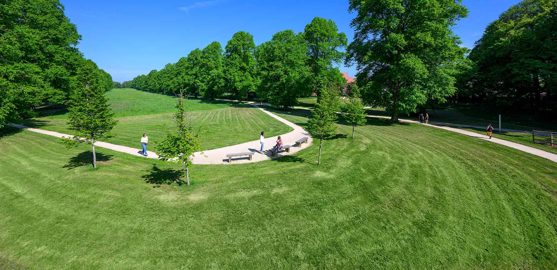 An exterior image of The Ride at Abbey Barn Park with people walking along the trail in the sun