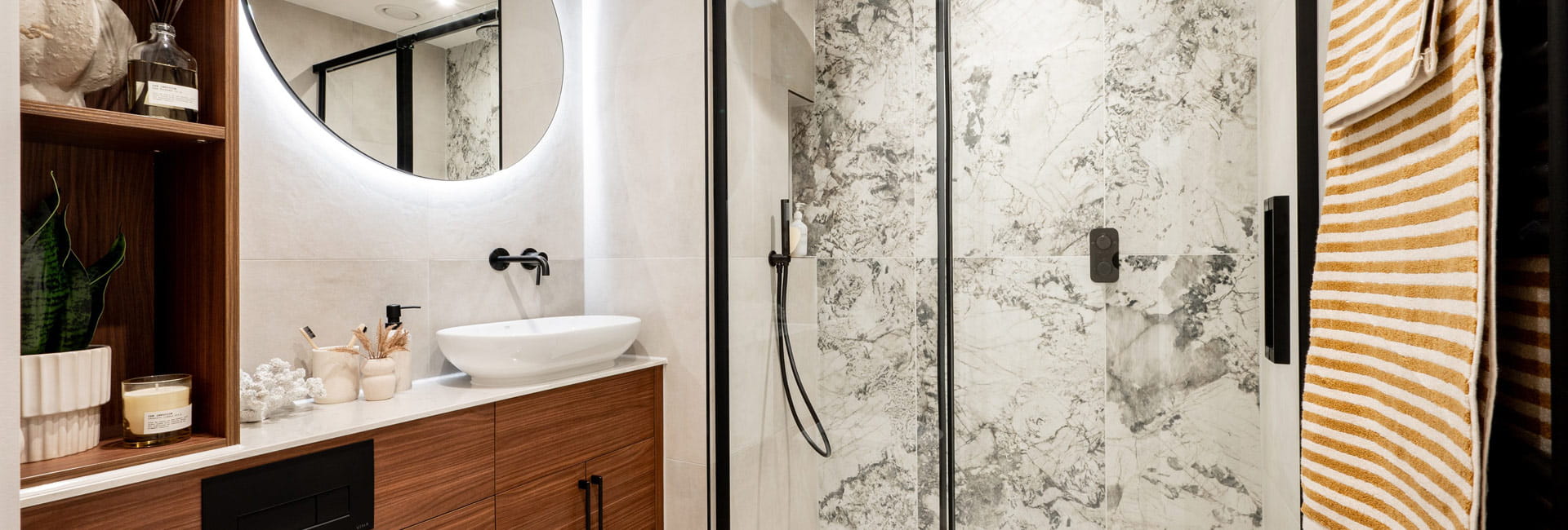 Modern designed bathroom with shower unit, wash basin with wall mirror, toilet and shelf space