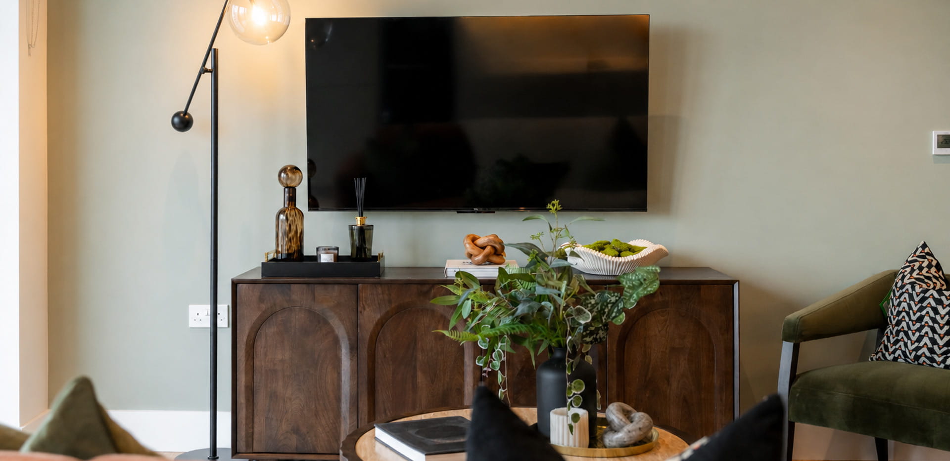 Coffee table and seating in foreground, wall mounted TV and storage unit behind.