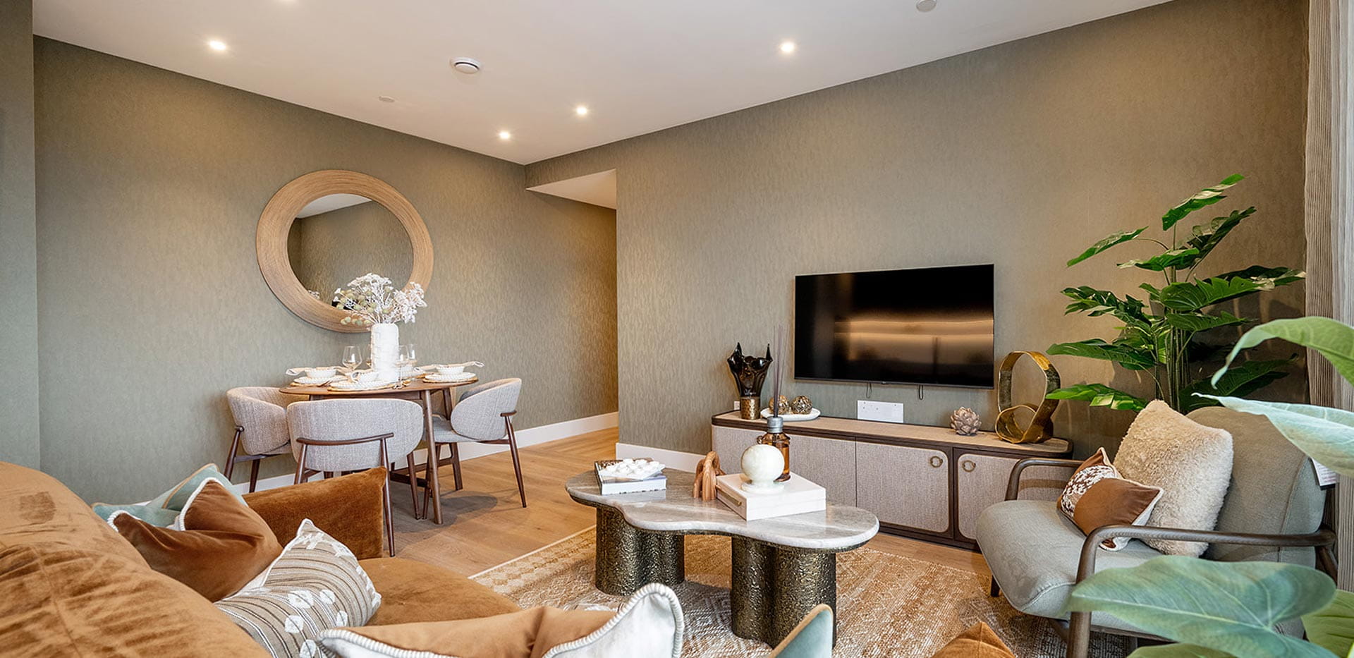 Modern designed living space with wall mounted TV and storage unit below, dining table adjacent to wall.